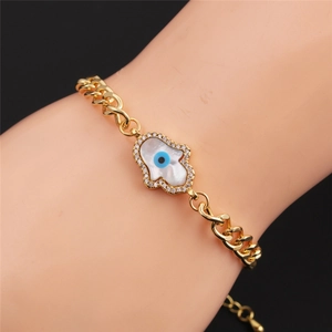 Detailed view of gold Hamsa Hand bracelet with blue Evil Eye and white shell inlay