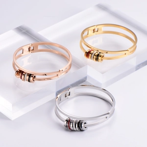 Sleek titanium steel bangles with rotating enamel rings in gold, silver, and rose gold finishes