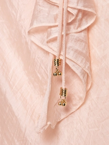 Macro detail of ruffled light peach dress with metallic beads and pleated satin texture