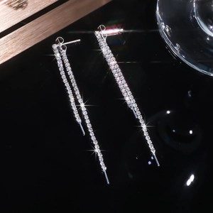 Exquisite long silver tassel earrings with sparkling crystals on a reflective black base