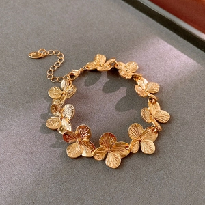 Detailed shot of golden flower bracelet featuring four-petal links and lobster clasp
