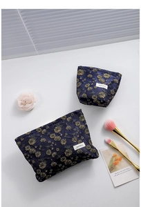 Detailed set of navy blue canvas cosmetic bags with golden daisy embroidery and zippers