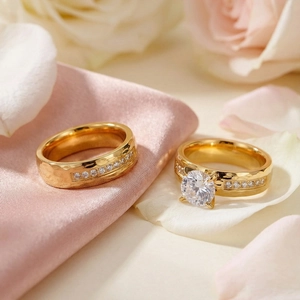 Close-up of gold titanium steel wedding ring set with zircon on pink silk background