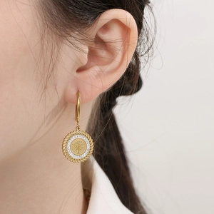 Close-up of golden 18K gold-plated steel tree of life earring with sparkling white zircons