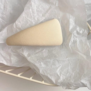 Detail of a beige twill fabric triangle hair clip on a clean white textured background