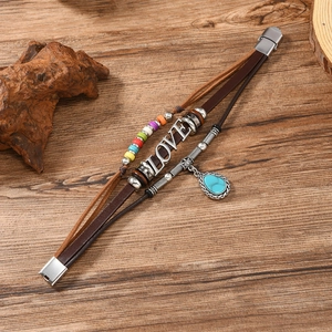 Detail view of a vintage Viking leather bracelet with Love charm and turquoise pendant