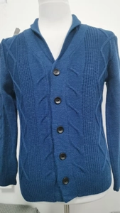 Nahaufnahme einer blauen Strickjacke mit Zopfmuster und hochwertigen schwarzen Knöpfen