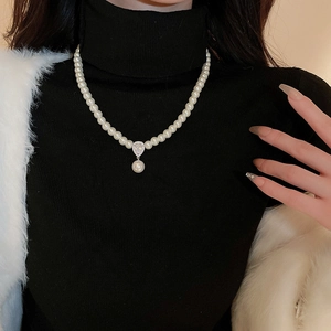 Close-up of pearl necklace with teardrop zircon pendant on a black turtleneck sweater