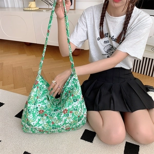 Detailed view of green floral canvas tote bag shown with model in home setting
