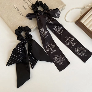 Detailed view of black silk bow scrunchies with white dots and floral patterns