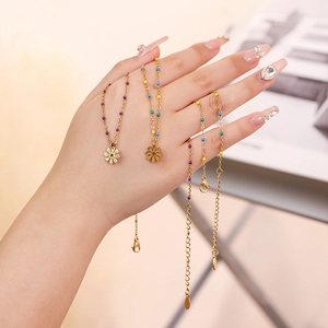 Detail of colorful beads and petal pendant on golden necklace held by hand