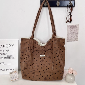 Detail of brown corduroy tote bag with heart patterns hanging on a white wall