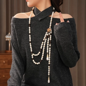 Close-up of vintage multi-layer pearl necklace with teardrop pendant on grey sweater