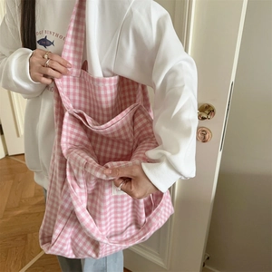 Detail of pink plaid tote bag with large front pocket showing fabric texture and size