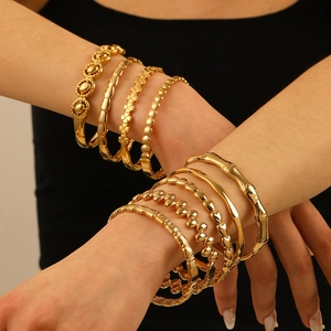 Ensemble de bracelets dorés avec motifs bambou et trèfle portés en superposition