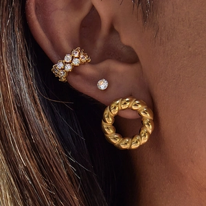 Close-up of gold ear cuff with diamonds and twisted hoop earring set for women