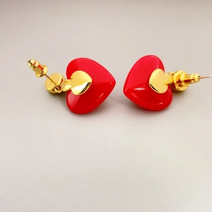 Detail of red heart-shaped earrings with gold metal accents and glossy texture