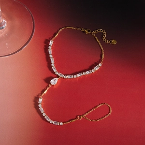 Detail of gold-plated stainless steel hand chain with baguette and pear-cut cubic zirconia