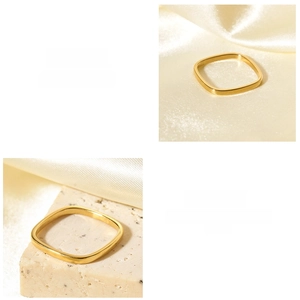 Detail of minimalist 18K gold square ring on silk and stone background textures