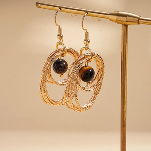 Detail of bohemian gold multi-layered circular drop earrings with tiger eye stone beads