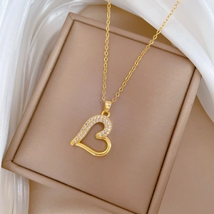 Elegant gold heart pendant necklace with zircon crystals on a white silk background