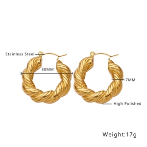 Detail of 30mm golden twisted stainless steel hoop earrings with high polish finish