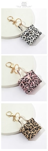 Three mini leopard print bag keychains in white, pink, and brown on a white display tray