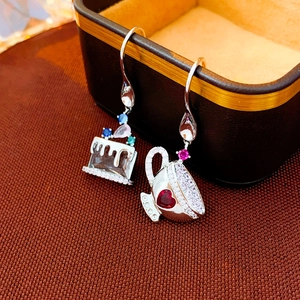 Vintage asymmetric cake and tea cup earrings with colorful zircons on a jewelry box