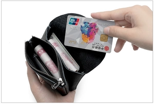 Close-up showing a hand inserting a credit card into the black soft leather mini coin purse
