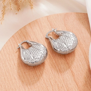 Vue détaillée de boucles d'oreilles argentées texturées sur un socle en bois clair