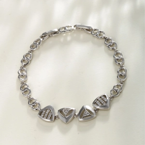Silver geometric triangle bracelet with sparkling zircon stones on a white textured background