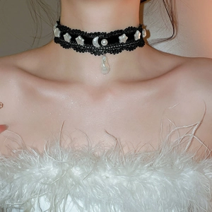 Détail du collier ras de cou en dentelle noire avec pendentifs étoile lune et perle