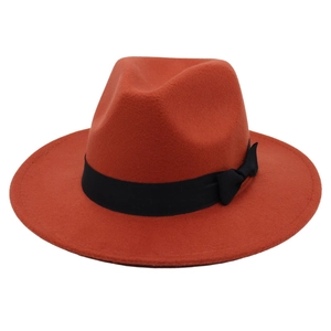 Orange-red wool jazz fedora hat with wide brim and black ribbon bow detail on white backdrop