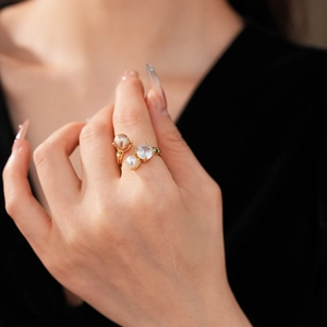 Détail d'une bague dorée ajustable avec perle champagne et zircon sur le doigt