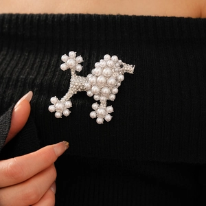 Detailed view of a vintage poodle brooch with pearls and rhinestones on black fabric