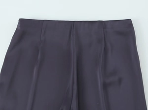 Détail d'un pantalon taille haute en satin violet foncé montrant la texture et les coutures