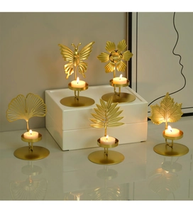 Detail of Nordic gold iron candle holders with butterfly and leaf motifs and warm tea lights