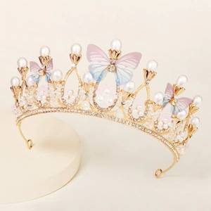 Detail of bridal crown with gold metal, pearls, and blue butterfly wings on a stand