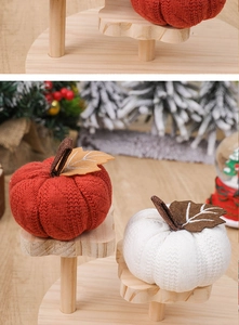 Detail of knitted harvest pumpkins on a wooden stand with festive autumn decorations