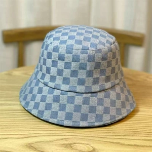 Detail of blue checkerboard denim bucket hat texture on a natural wooden table