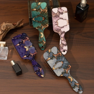 Detailed top view of four air cushion hair brushes with diverse marble patterns on wood