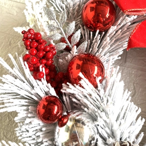 Detailed close-up of Christmas wreath featuring red berries and snow-flocked pine needles