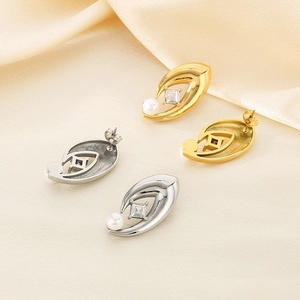 Detail view of 18K gold and silver oval earrings with white pearl and square zircon inlay