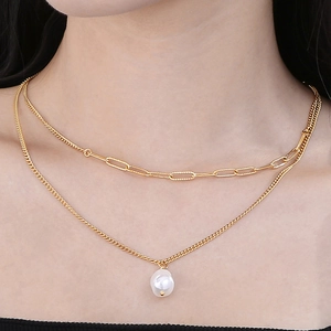 Close-up of a layered gold paperclip chain necklace with a baroque pearl pendant for women