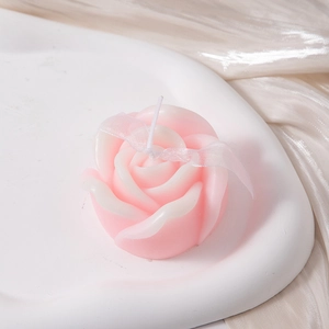 Close-up of a pink gradient rose-shaped scented candle on an elegant white tray