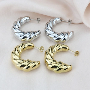Minimalist twisted croissant earrings in polished gold and silver finishes on silk