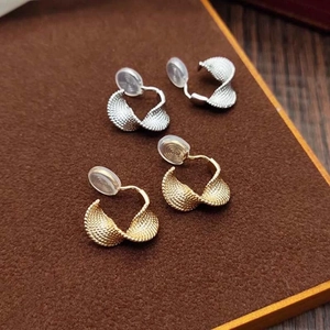 Detailed macro view of spiral gold and silver clip-on earrings with textured metal surface