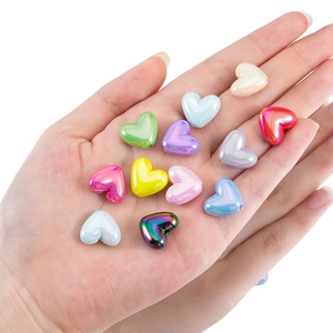 Colorful iridescent heart acrylic beads held in hand for DIY jewelry making material