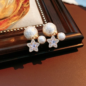 Macro view of 18K gold-plated earrings with cotton pearls and zircon star charm