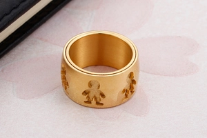 Close-up of golden wide band ring featuring brushed texture and hollowed human figures